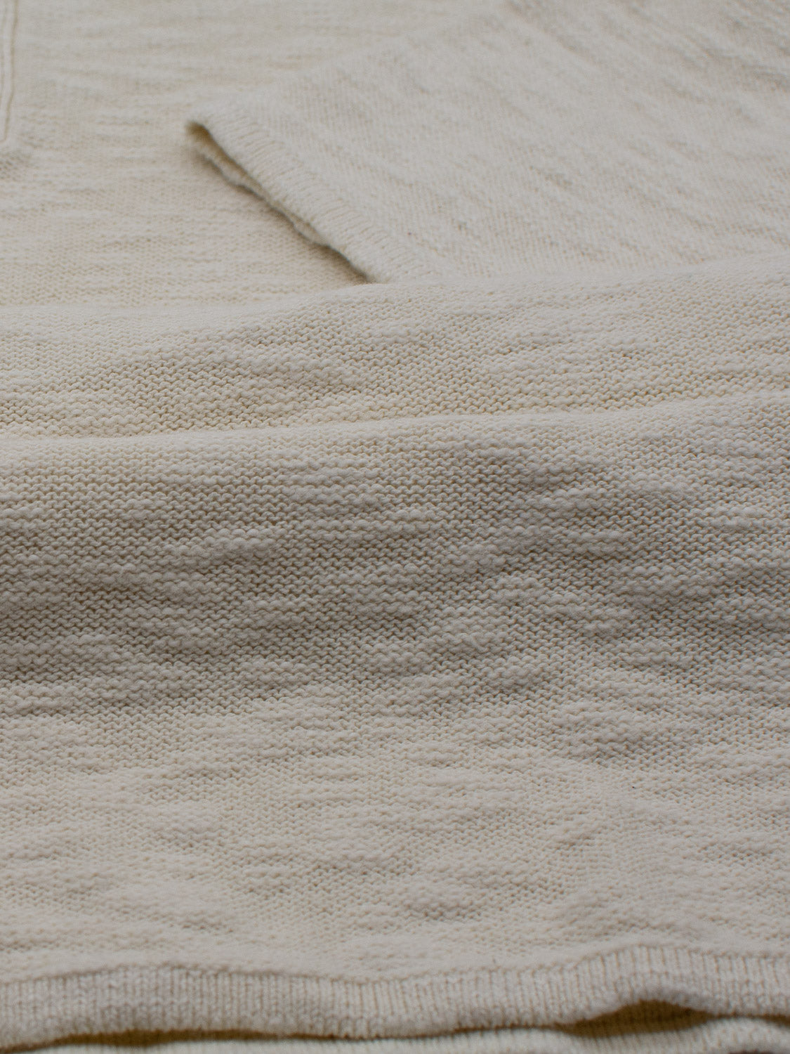 A close-up of the Miami Reverse Knit Cotton Polo by ID Menswear showcases its cream-colored knit, featuring a textured pattern ideal for casual wear. The focus on its surface highlights a soft, cozy appearance, promising breathability and comfort.