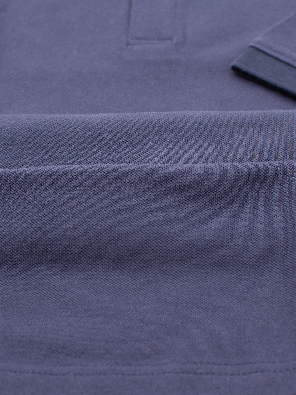 A close-up of the Ranger Classic Cotton Mesh Polo by ID Menswear showcases its classic style in dark blue. The lightweight cotton fabric, with visible stitching and a tucked under collar, highlights the woven pattern and rich color.