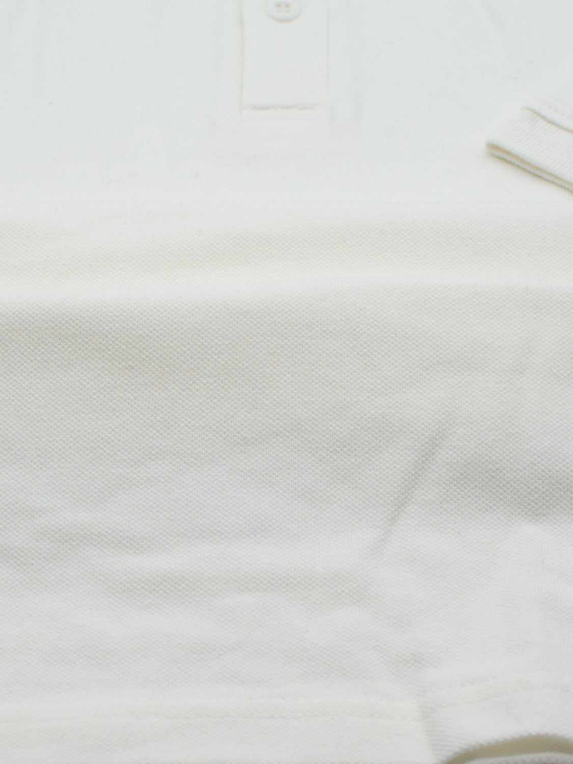 Close-up of the Ranger Classic Cotton Mesh Polo by ID Menswear, highlighting its lightweight cotton fabric with a textured surface and partial collar adorned with buttons, emphasizing its soft texture and subtle stitching.