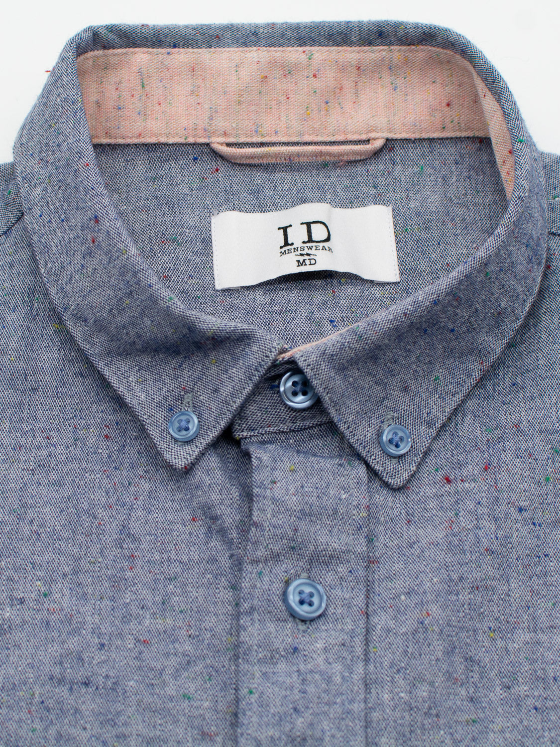Close-up of the Allswell Speckled Button Down Shirt by ID Menswear, made from a premium cotton-linen blend. It has blue buttons, multicolored speckles, and a pink inner collar with an I.D tag in medium size. Perfect for any occasion.