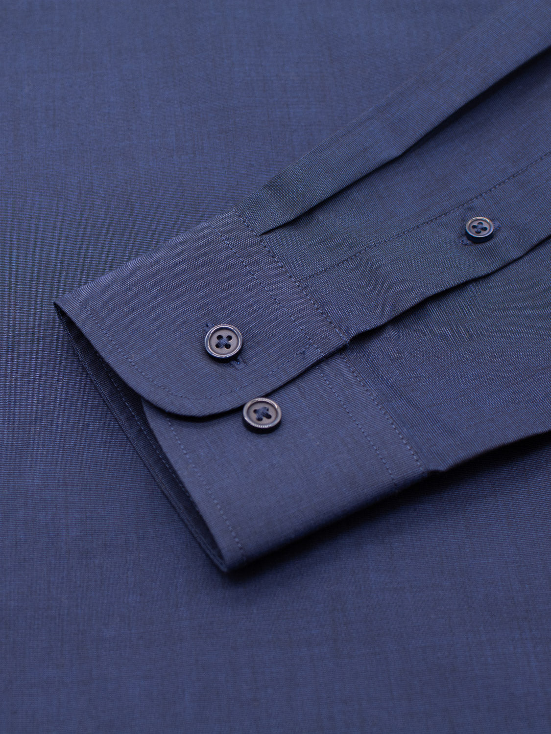 A close-up of the ID Menswear Cotton Dress Shirt in Slim Fit, featuring a long-sleeve blue cuff with two dark buttons, displayed flat on a matching blue background.