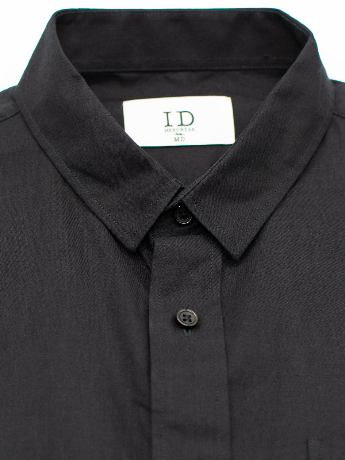 Close-up of a sleek black button-up shirt featuring a classic collar and breathable fabric. The label reads ID Menswear. Two visible buttons near the center highlight its design. This is the Goa Linen Cotton Long Sleeve Shirt by ID Menswear.