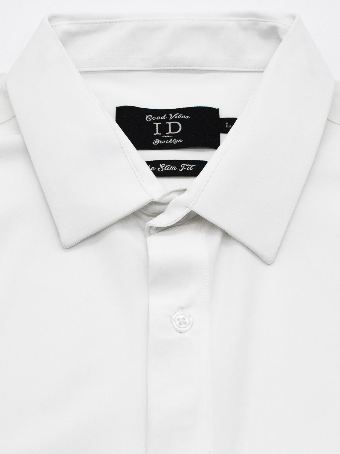 A neatly folded, white long-sleeve button-up dress shirt features a pointed collar and a visible top button. The black label, with white text, identifies it as the Axel 4-Way Stretch Dress Shirt by ID Menswear, designed for comfort in slim-fit style.