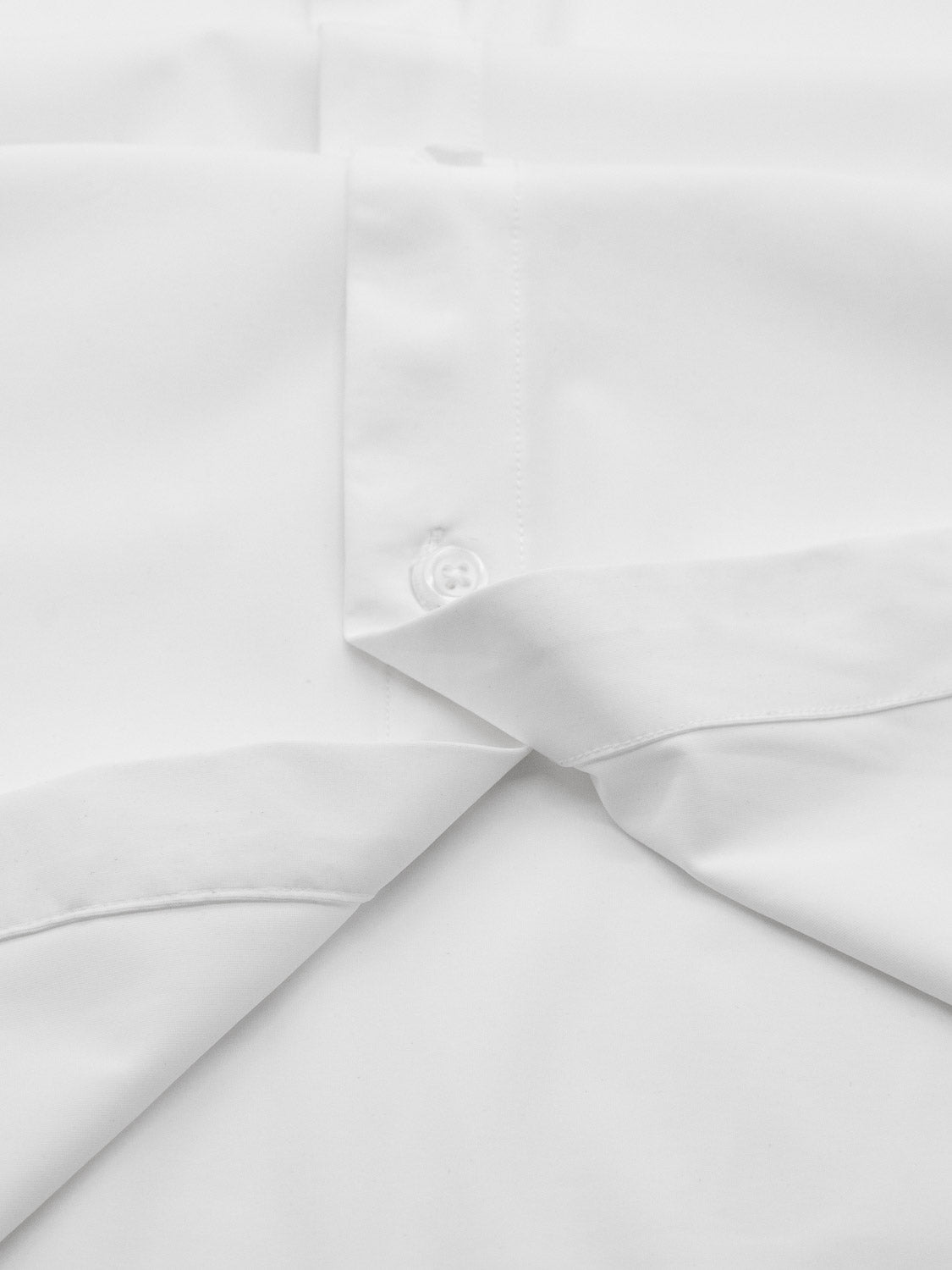Close-up of the ID Menswear Axel 4-Way Stretch Dress Shirt in white, featuring a button and folded collar. The smooth fabric provides a crisp, clean texture and comfortable wear with its 4-way stretch.