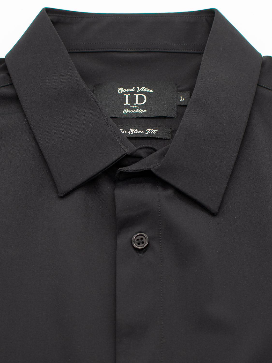 Close-up of a neatly buttoned black Axel 4-Way Stretch Dress Shirt from ID Menswear, featuring a stiff collar and Good Vibes label. With its slim fit and comfortable stretch, this shirt is both stylish and practical.