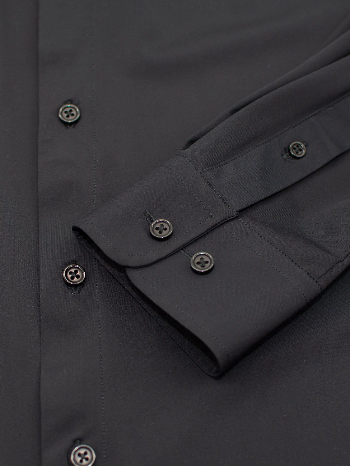 Close-up of the Axel 4-Way Stretch Dress Shirt by ID Menswear: a black slim-fit long-sleeve with two-button cuffs, smooth texture, and black front buttons for comfortable wear.