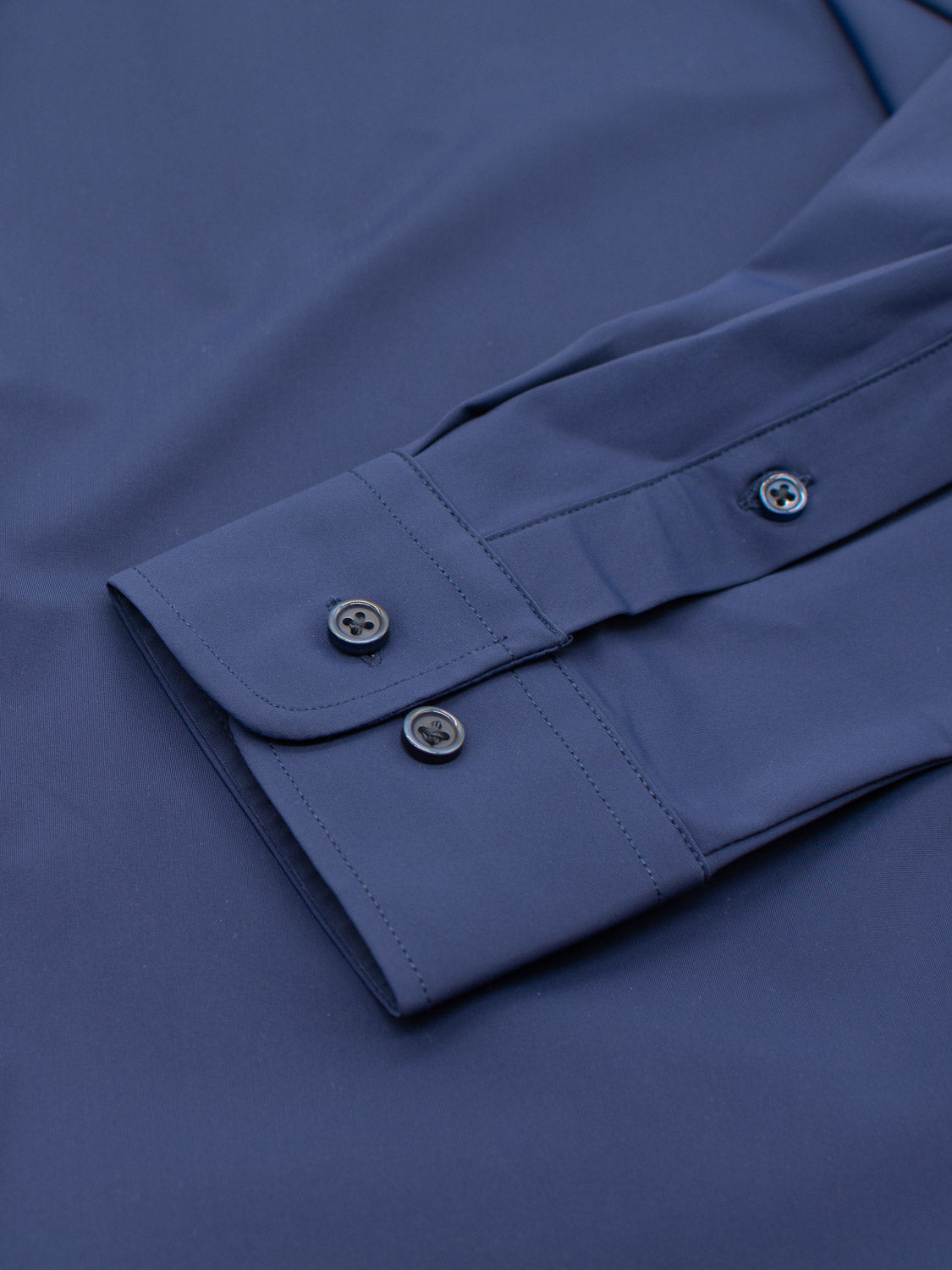 Close-up of the Axel 4-Way Stretch Dress Shirt by ID Menswear in blue, highlighting a slim-fit with adjustable two-button folded cuff. The smooth fabric showcases detailed stitching and buttons for comfort.