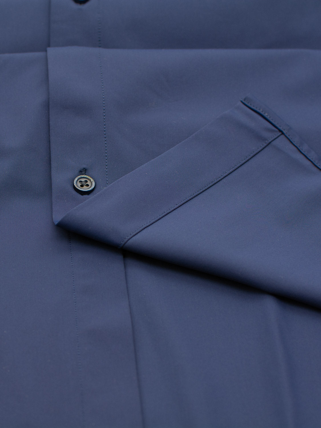 Close-up of the Axel 4-Way Stretch Dress Shirt by ID Menswear in dark blue. It features a slim fit with a smooth fabric, chest pocket slightly angled, and a single button near the edge for comfortable wear that moves with you.