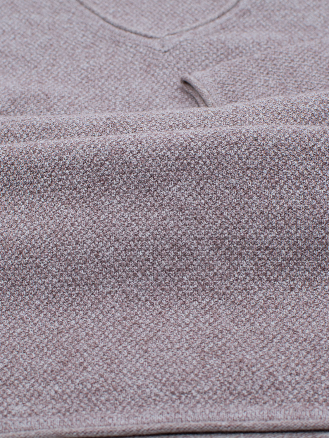 Close-up of a folded sweater in soft beige, featuring a waffle-knit from ID Menswears Amalfi Deep V Knitted Top, showing the edge of its V-neckline. The linen and cotton blend adds texture to this long-sleeve piece.