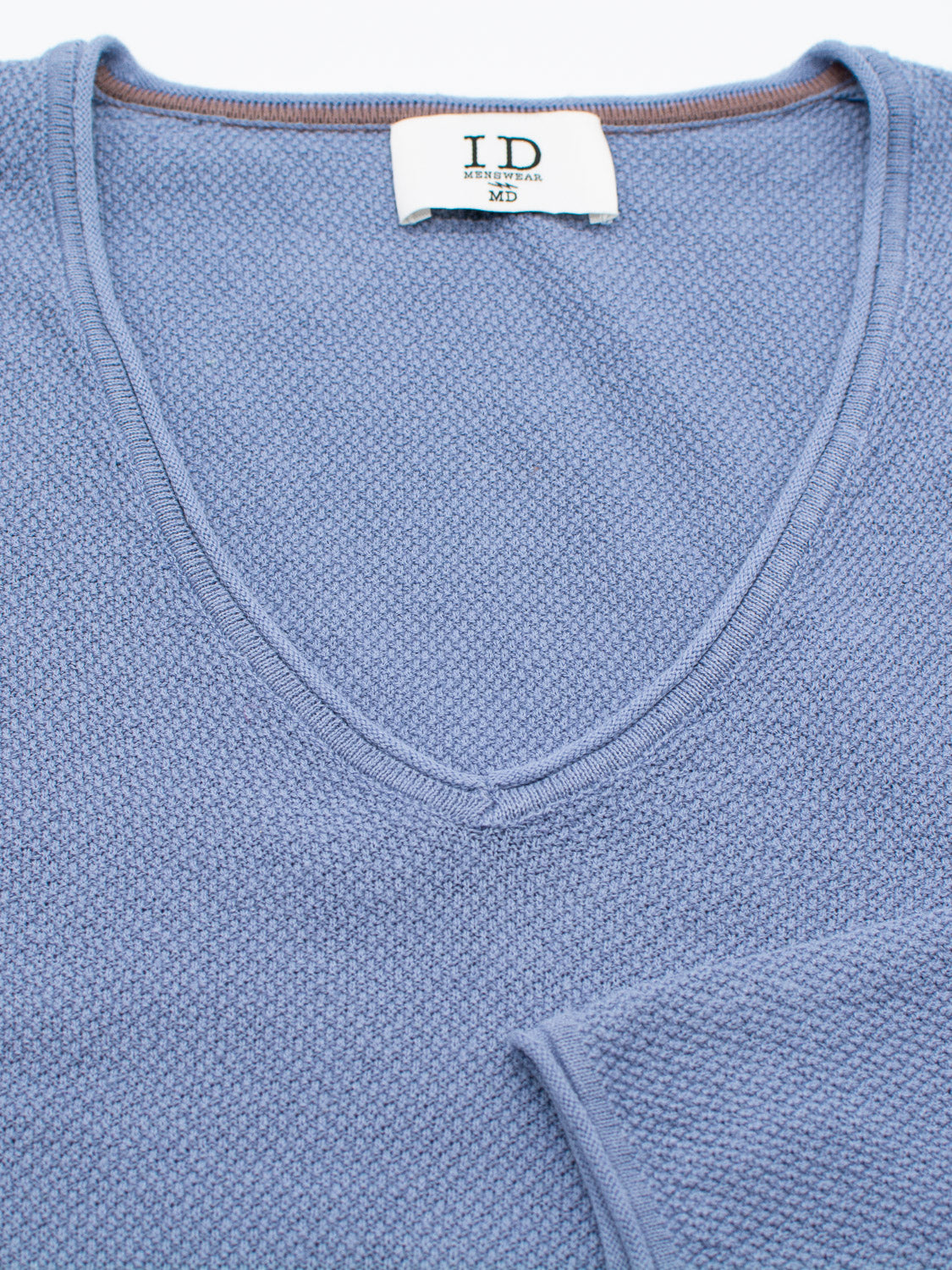 Close-up of a light blue Amalfi Deep V Knitted Top featuring a textured pattern, made from a soft linen-cotton blend. The label inside the collar reads ID Menswear M3.