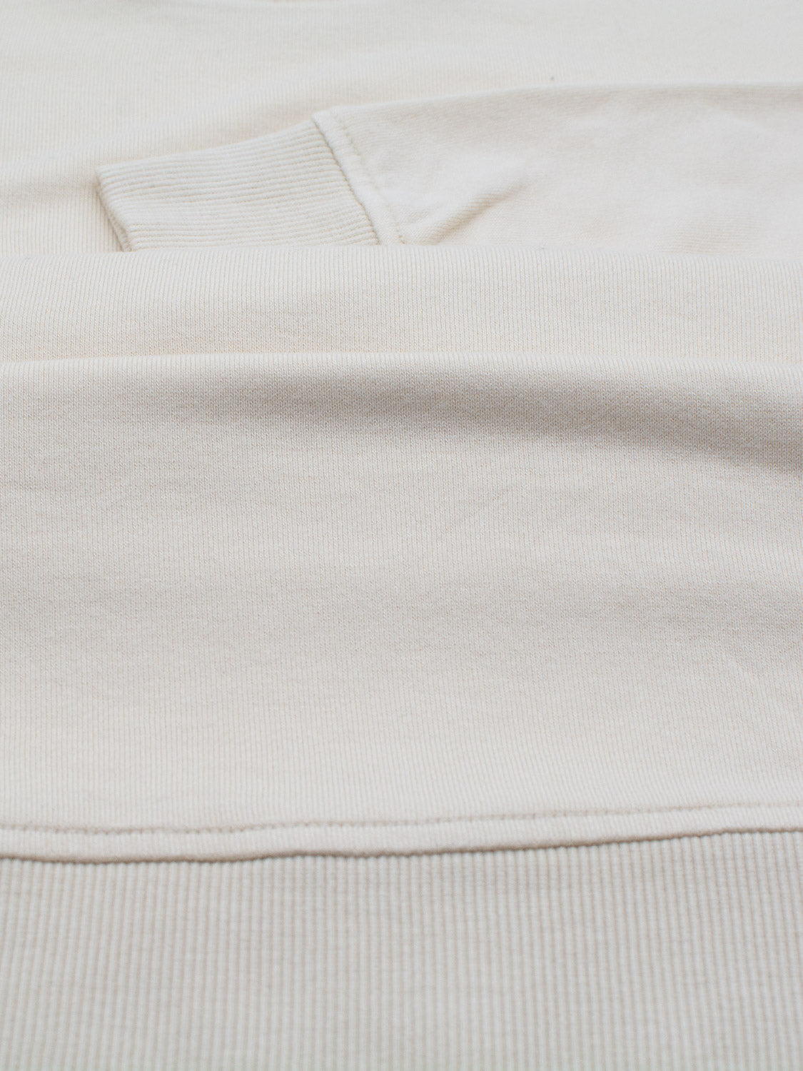Close-up of a ribbed beige fabric, part of the Champ Bamboo Organic Cotton Sweatshirt by ID Menswear. The seam with visible stitching suggests its a garment like a sweatshirt or sweater.