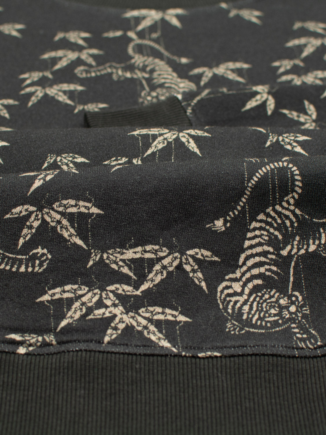 Close-up of the ID Menswear Tiger Bamboo Printed Sweatshirt: black fabric with white tigers and bamboo, reminiscent of a Japanese design. The small, repetitive pattern is crafted from soft Bamboo Fleece for ultimate comfort.