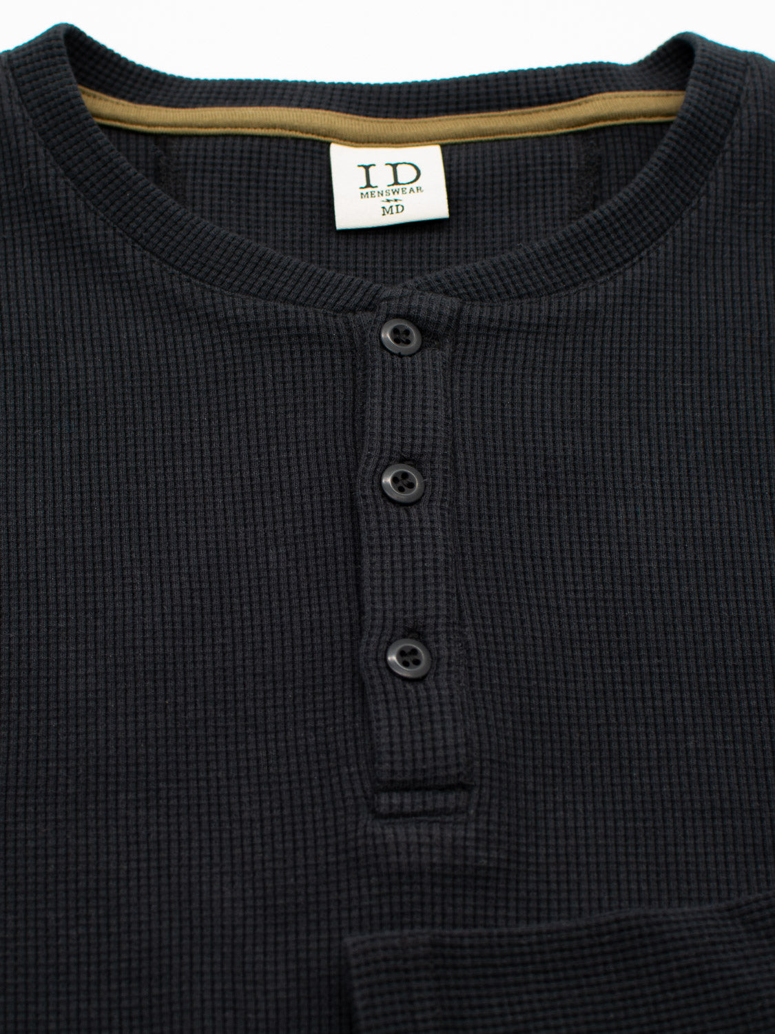 The Freestyle Waffle Knit Henley by ID Menswear is a black, regular-fit shirt with a round neckline and four buttons. Made from a cotton-spandex blend, it features a visible medium size tag and an additional partially hidden label.