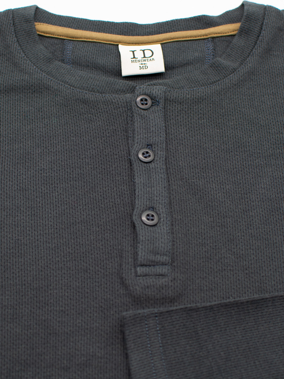 Close-up of ID Menswears Freestyle Honeycomb Knitted Mesh Henley in bamboo charcoal gray. It features a ribbed texture, three dark buttons, a tan inner neckline, and a visible MD size tag, showcasing its organic cotton comfort.