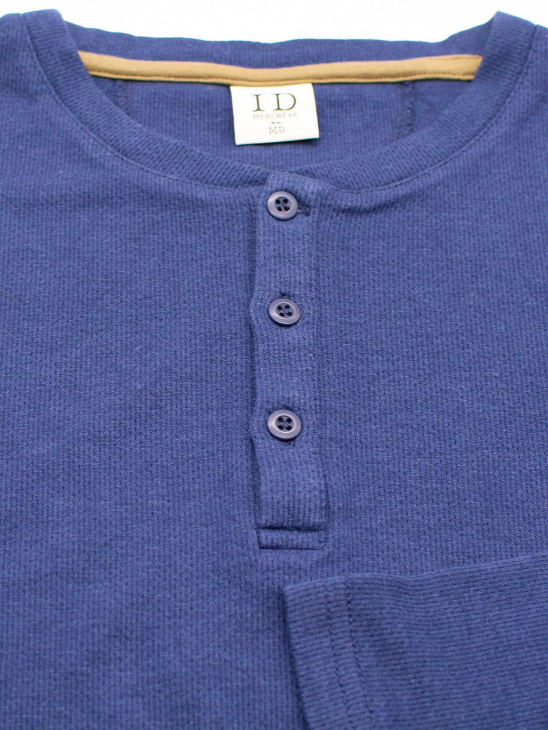 The Freestyle Honeycomb Knitted Mesh Henley by ID Menswear is a blue mens shirt made from organic cotton. It features a ribbed texture, four-button placket, size medium label at the collar, and a brown accent inside the neckline.