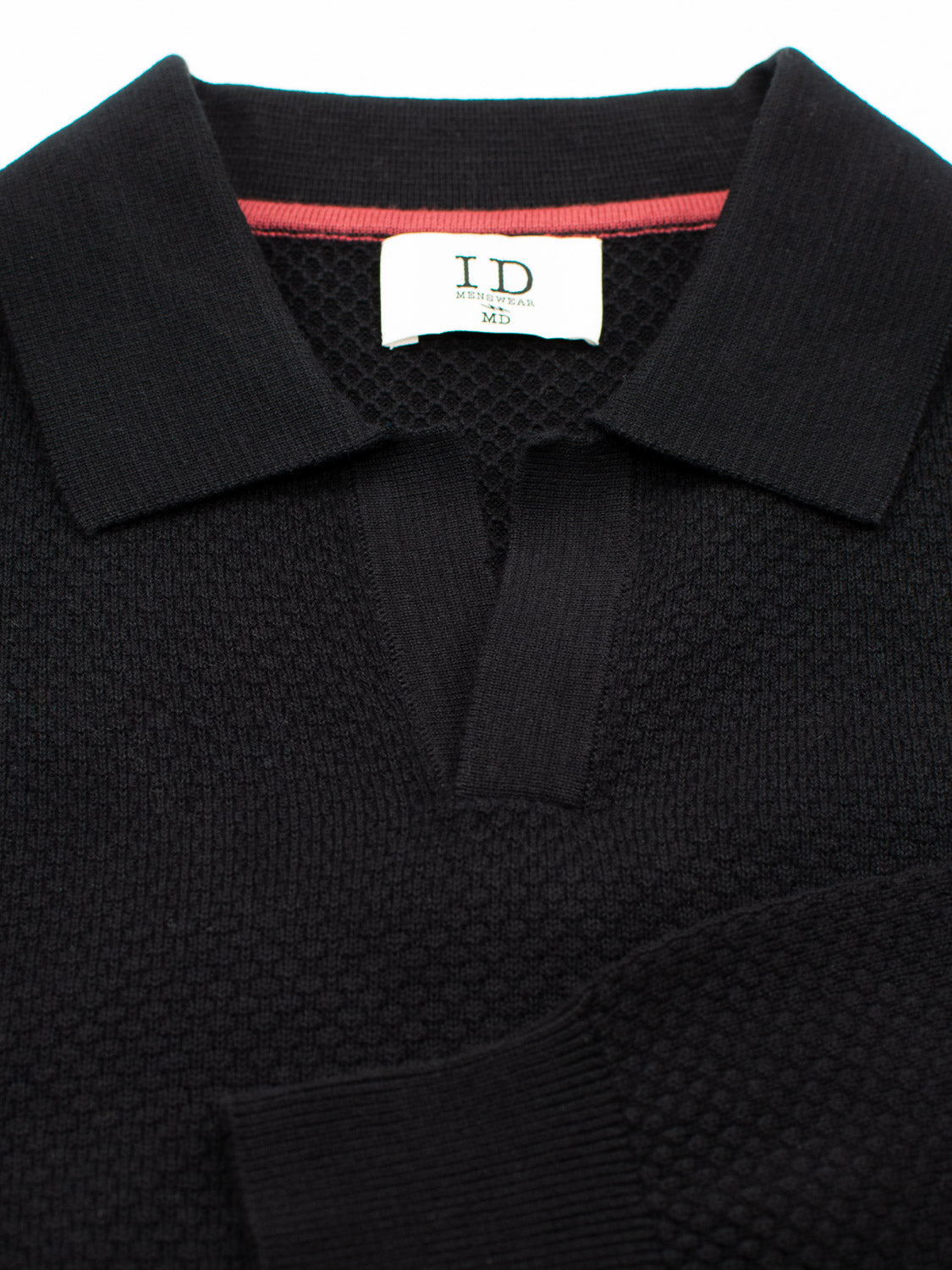 A black textured cotton polo shirt from ID Menswear, perfect for smart-casual events and Seattle weather. It features a folded collar with red trim and a Made in Italy label. The Seattle Long Sleeve Cotton Polo is neatly displayed on a flat surface.
