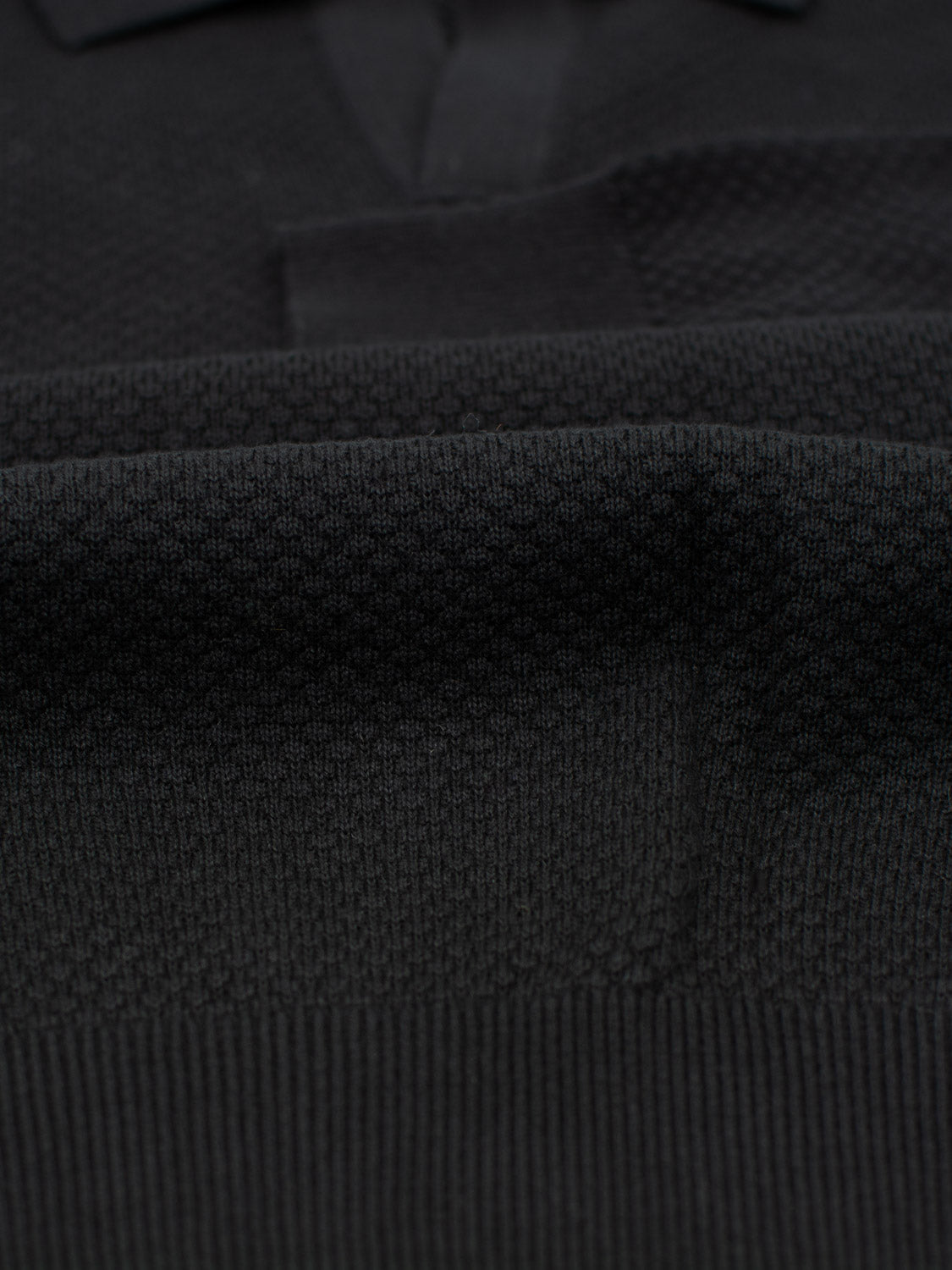 Close-up of the black textured fabric for ID Menswears Seattle Long Sleeve Cotton Polo, showcasing its raised, patterned surface with deep color and detailed texture, perfect for smart-casual occasions.