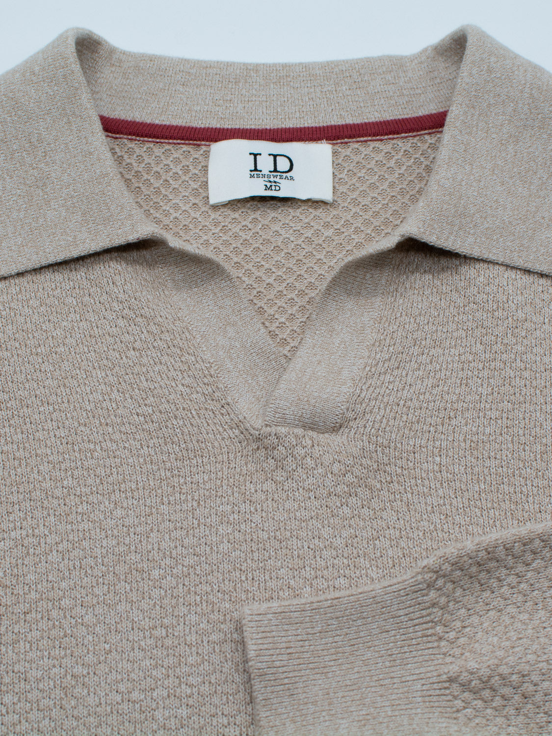 Beige knit sweater laid flat, features a textured collar and red trim. Ideal for smart-casual events, it evokes the classic style of a Seattle Long Sleeve Cotton Polo. Visible tag shows ID Menswear.