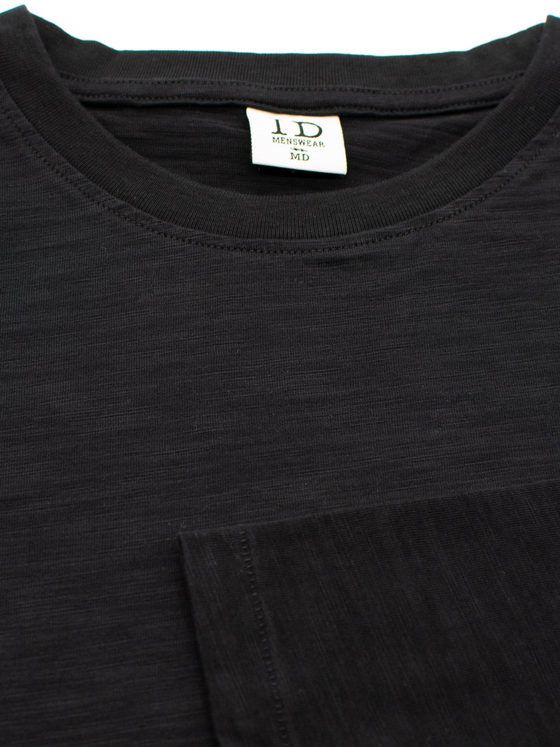 A close-up of the black Paradise Long Sleeve Tee from ID Menswear highlights a visible neckline and a front pocket. The soft, slightly textured fabric enhances its appeal, perfect for casual wear.