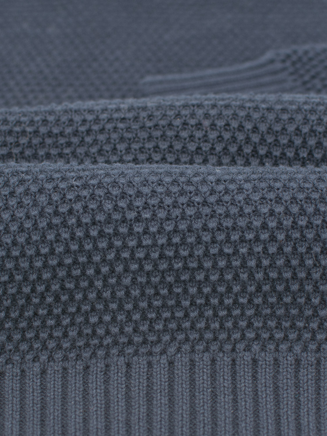 Close-up of ID Menswears Quebec Chunky Sweater in dark blue, showcasing a textured fabric with subtle honeycomb patterns at the top and cozy ribbed details at the bottom, highlighting intricate knitwork.