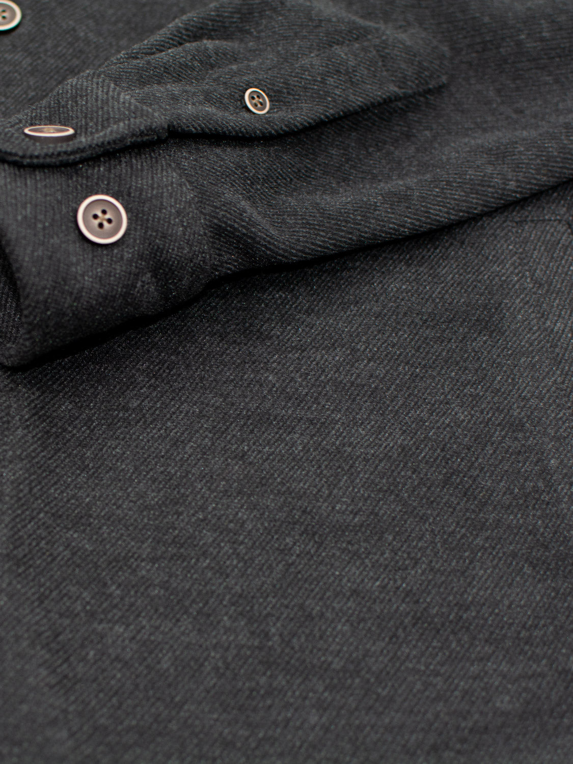Close-up of ID Menswears Yukon Shirt Jacket in dark grey, featuring a subtly textured fabric and visible round sleeve buttons. Ideal for casual outings and transitional weather; the blurred sleeve adds an intriguing touch to the image.