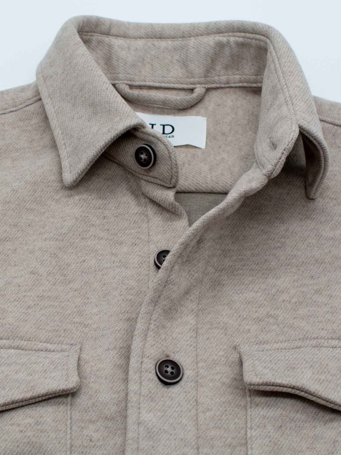 Perfect for casual outings in transitional weather, this beige button-up flannel shirt from ID Menswears Yukon Shirt Jacket line features front pockets and a visible tag under the collar.
