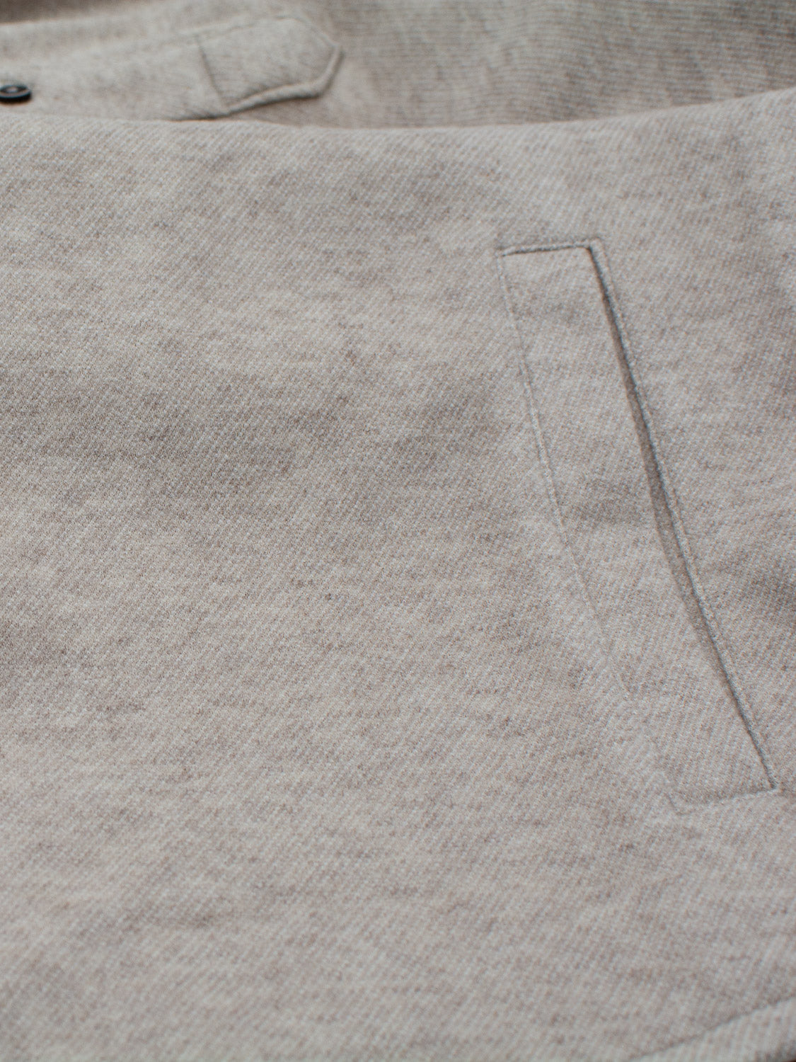 Close-up of the light gray textured fabric of the ID Menswear Yukon Shirt Jacket, featuring a straight seam and rectangular pocket. Ideal for casual outings in transitional weather, it offers a subtle pattern for a minimalist appearance.