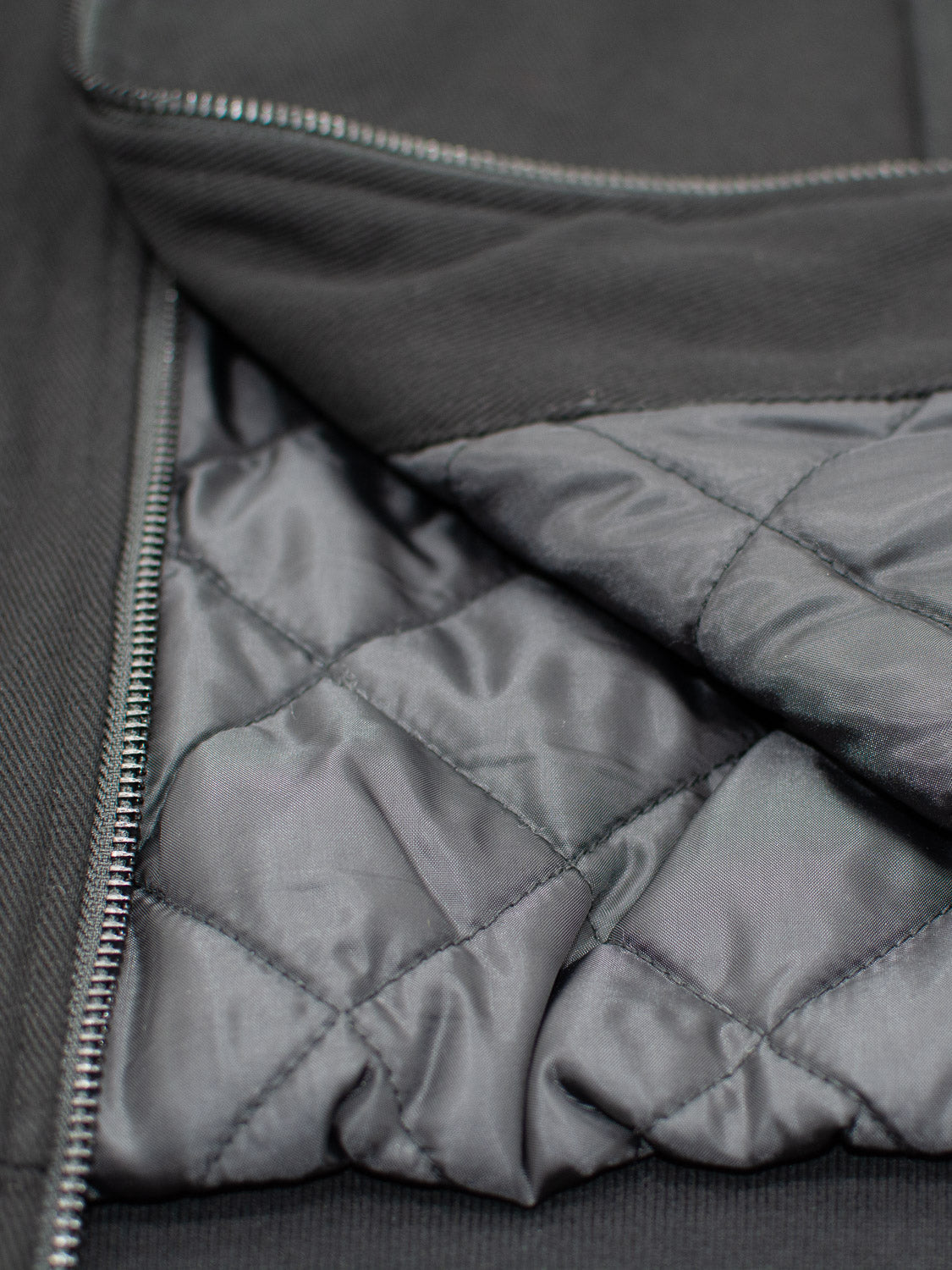Close-up of the Yonkers Cotton Canvas Jacket by ID Menswear, showcasing its quilted, cotton-padded lining. The image highlights the texture and stitching patterns of the interior fabric, with a partially visible silver zipper on the side.