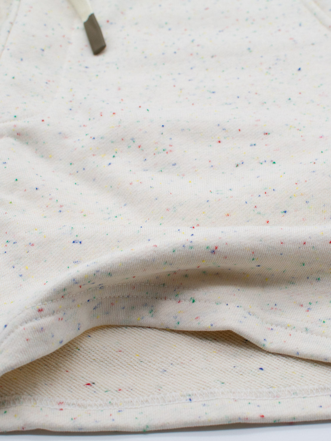 The Waikiki Speckled Cotton Short by ID Menswear features fashion-forward cream cotton yarn with multicolored speckles and a metal-tipped drawstring that weaves through its softly textured folds, offering a casual yet comfortable style.