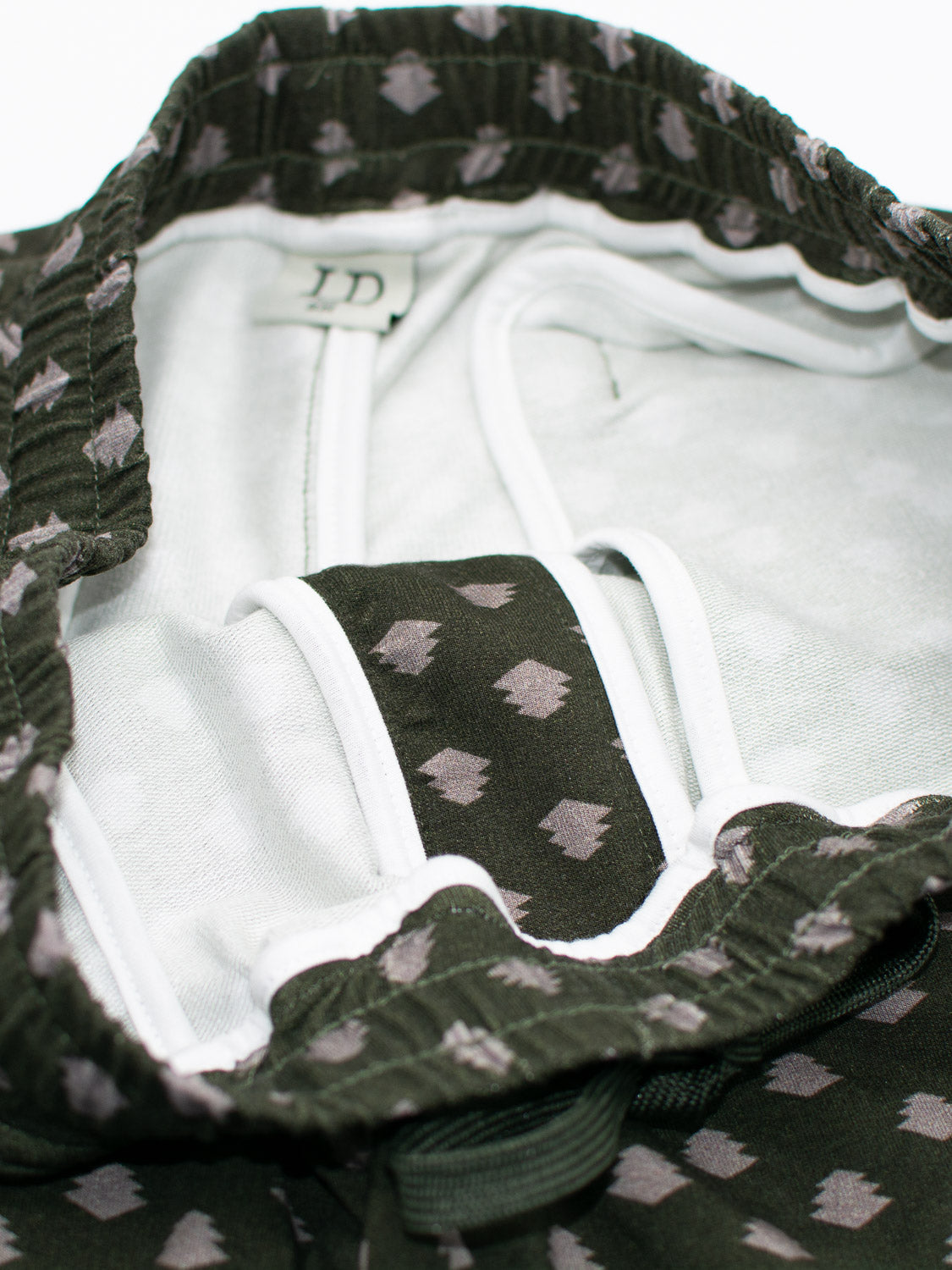 Close-up of ID Menswears Samui Vintage Japanese Print Short in green bamboo fabric. The interior shows a white lining and small white shapes in a vintage Japanese style, highlighting its soft texture with visible waistband and seams.