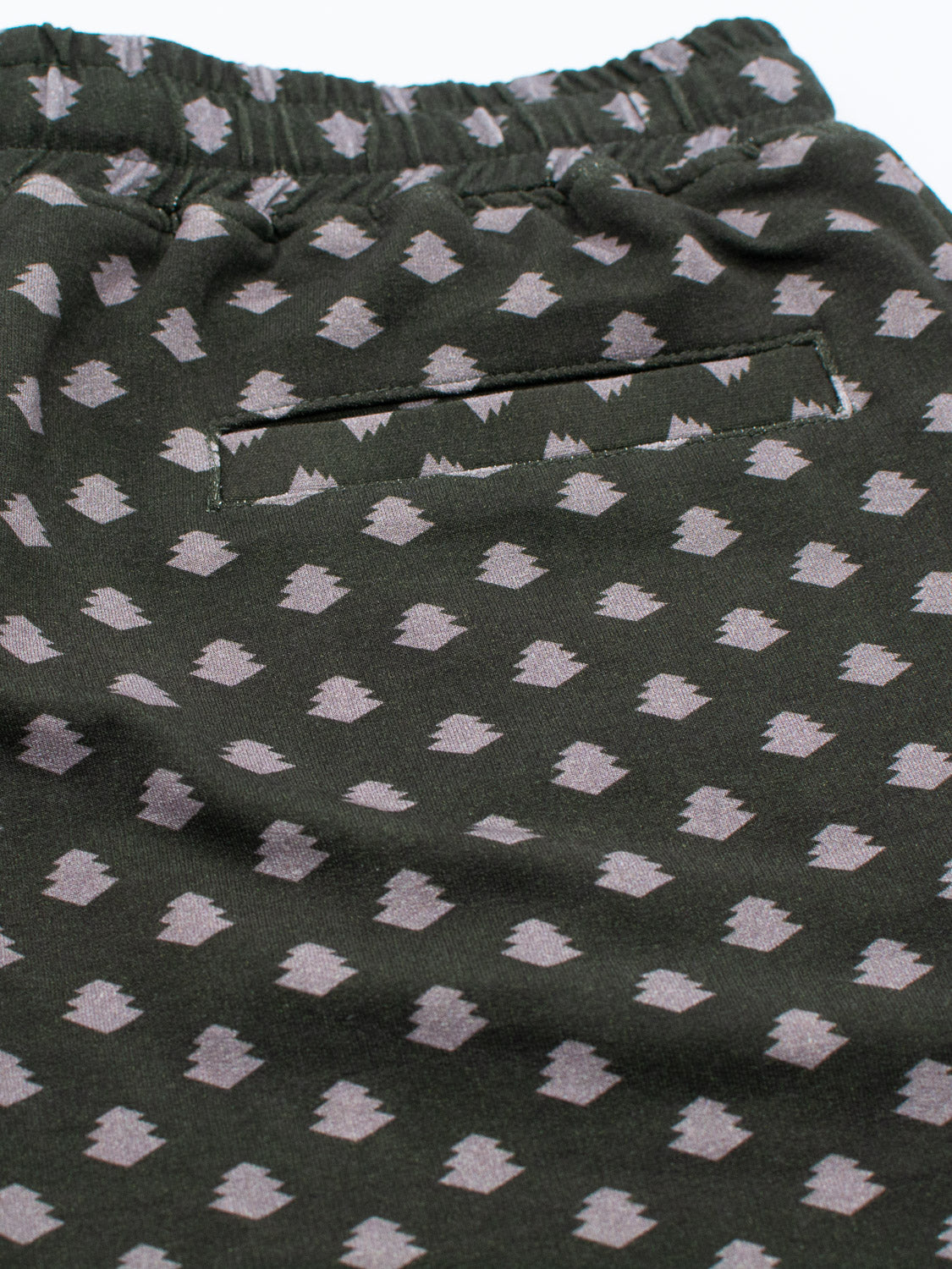 A close-up of ID Menswears Samui Vintage Japanese Print Short, made from organic cotton. It showcases dark green fabric with light gray diamond shapes, an elastic waistband, and a flat back pocket, capturing the essence of vintage Japanese print.