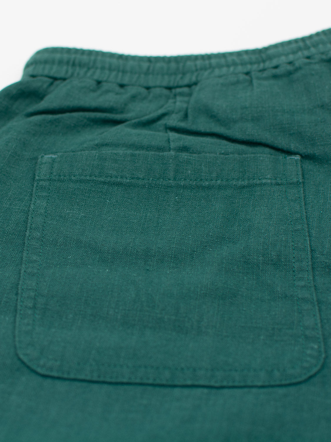 Introducing the Phi Phi Linen Blend Drawstring Short by ID Menswear—green fabric shorts with an elastic waistband, a 6 inseam, and a square back pocket. Featuring simple, clean stitching and soft texture in a deep, rich green color.