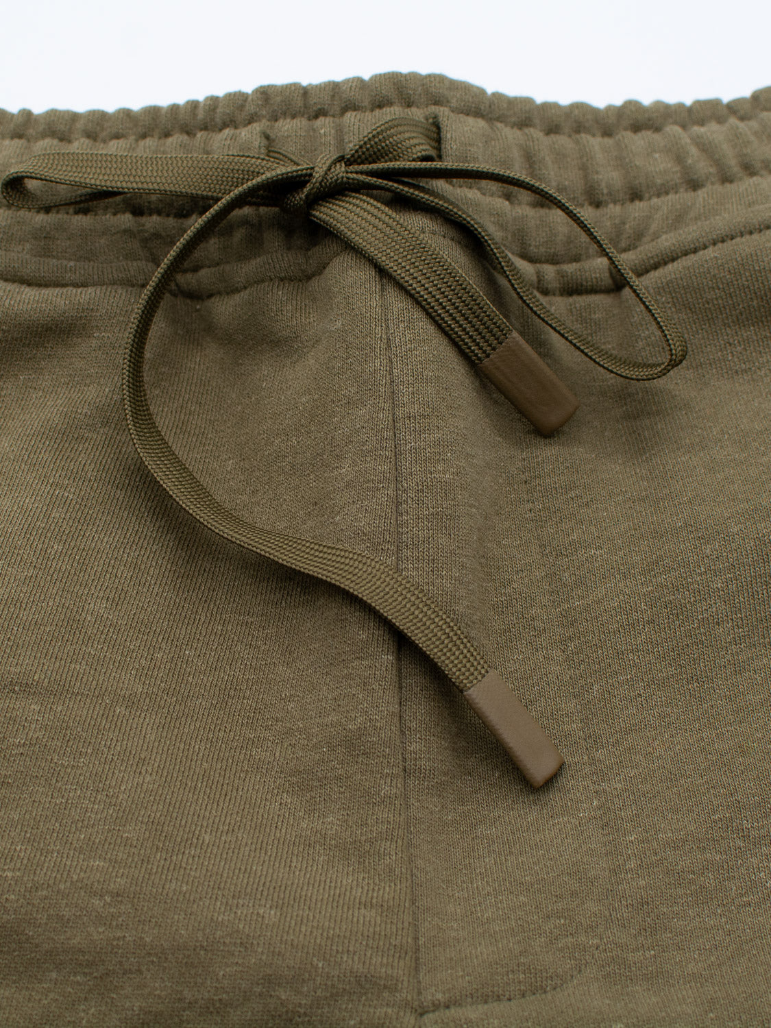 Close-up of Walker Hemp Cotton Terry Short by ID Menswear: olive-green with an elastic waistband, matching drawstring with coated tips at the center. Made from organic cotton, the fabric is soft with a slightly textured look.