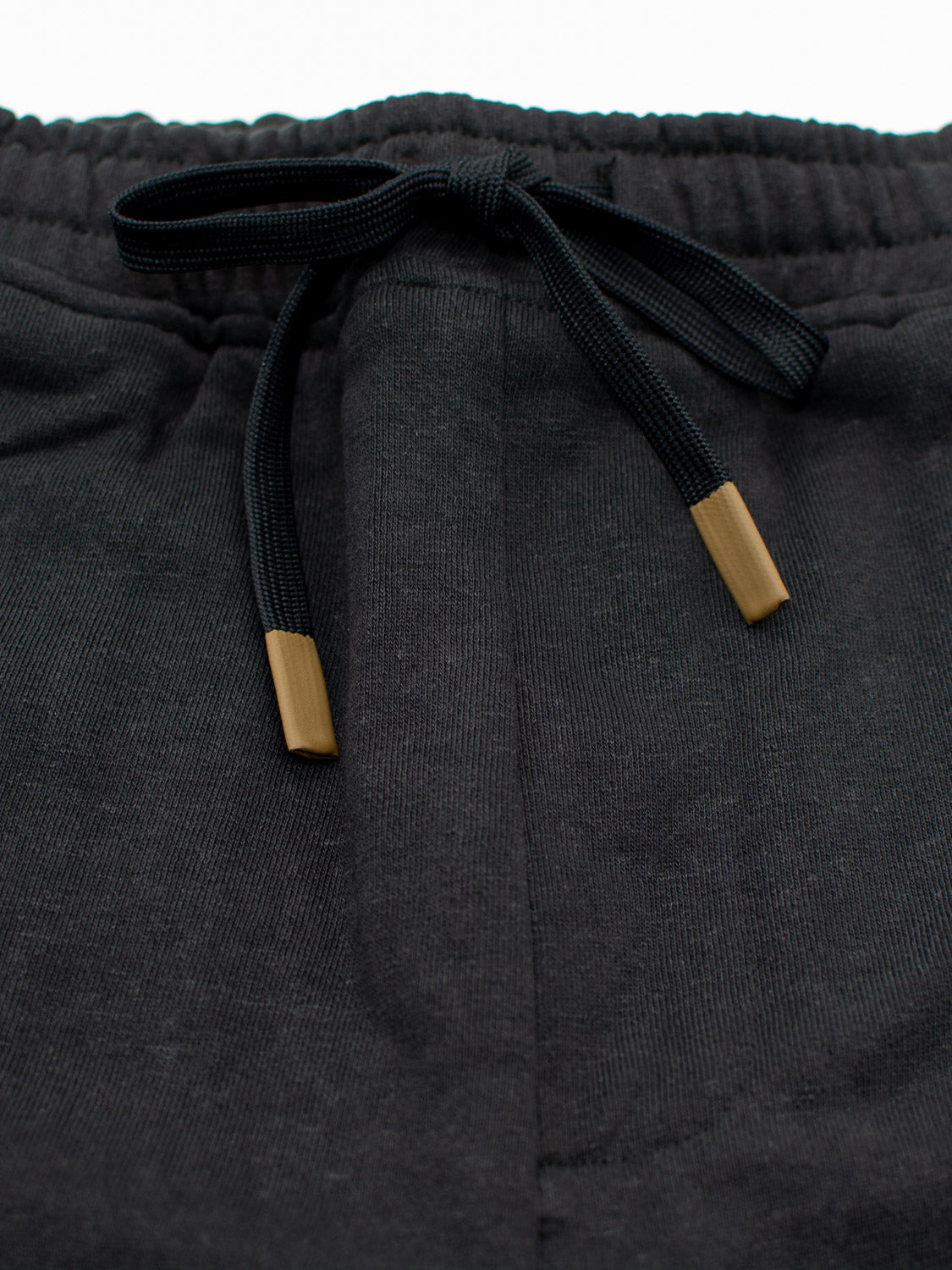 Close-up of the waistband of the Walker Hemp Cotton Terry Short by ID Menswear, showcasing an elastic band and drawstring with gold-tipped ends. Made from organic cotton, the fabric looks soft and comfortable for casual wear in a dark gray shade.