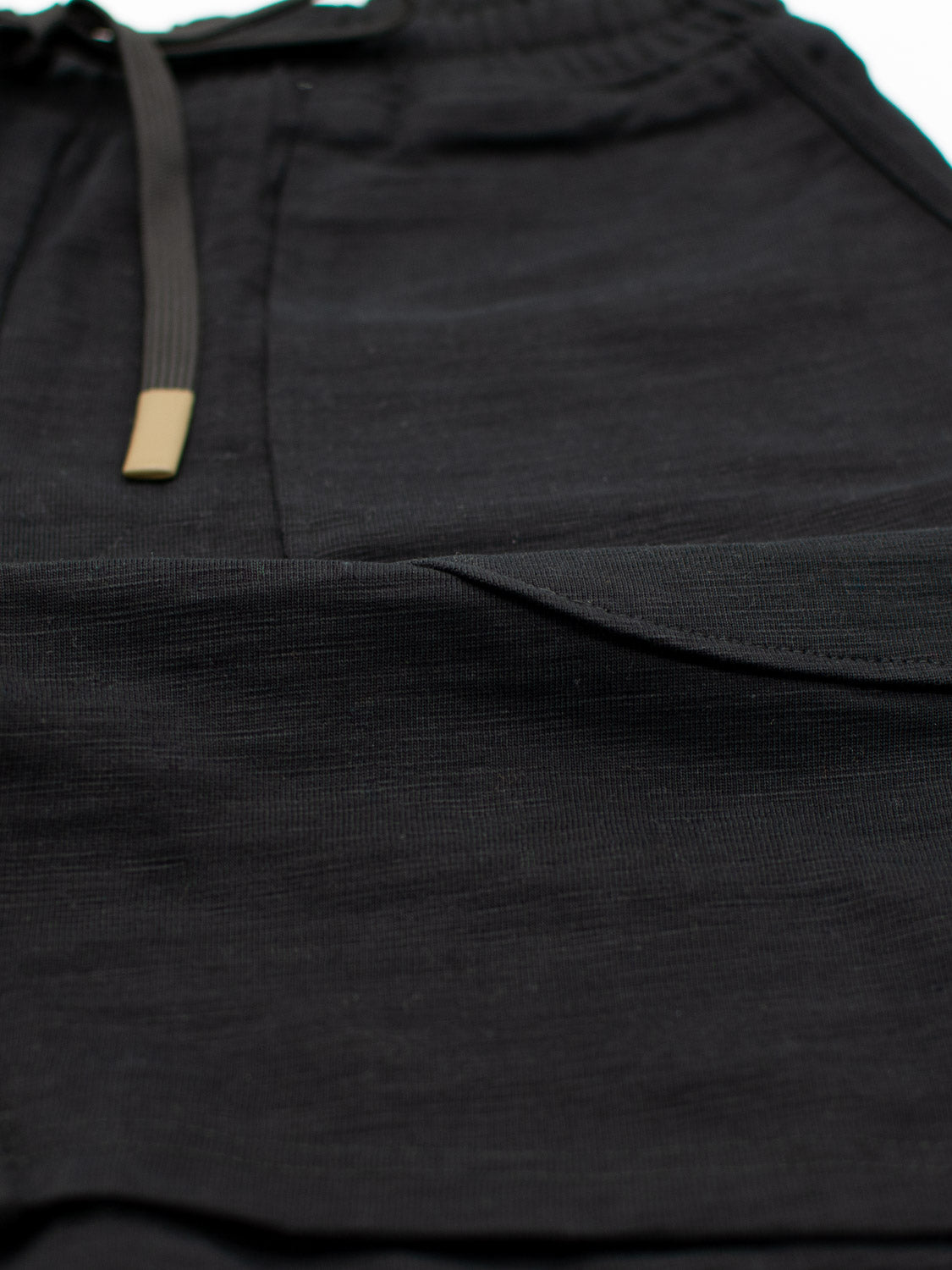 Close-up of Kahala Slub Cotton Drawstring Shorts by ID Menswear, highlighting the textured black slub cotton fabric with a metallic tip drawstring for a relaxed fit around the waistband and leg.