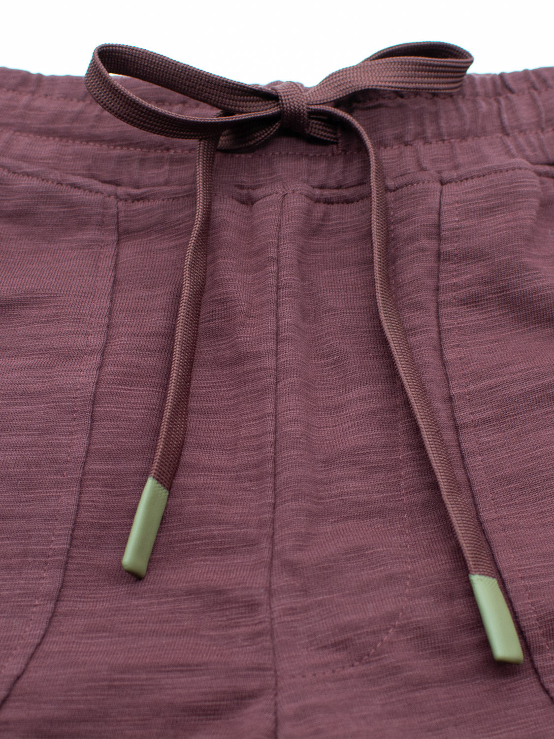 Close-up of the Kahala Slub Cotton Drawstring Short by ID Menswear shows maroon shorts in textured slub cotton with a relaxed fit, a drawstring waist, and green-tipped strings.