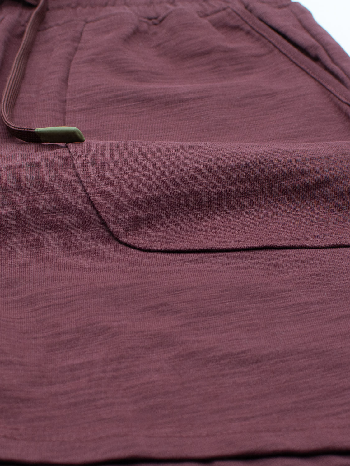 Close-up of ID Menswears Kahala Slub Cotton Drawstring Short in maroon, featuring a flap pocket. Made from subtly textured slub cotton for a relaxed fit, the neatly sewn pocket flap highlights the craftsmanship.