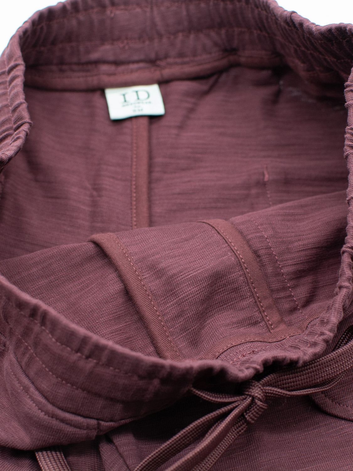 Close-up of a maroon Kahala slub cotton drawstring hood, showcasing the stitching and texture, with an ID Menswear label inside. The design complements its relaxed fit.