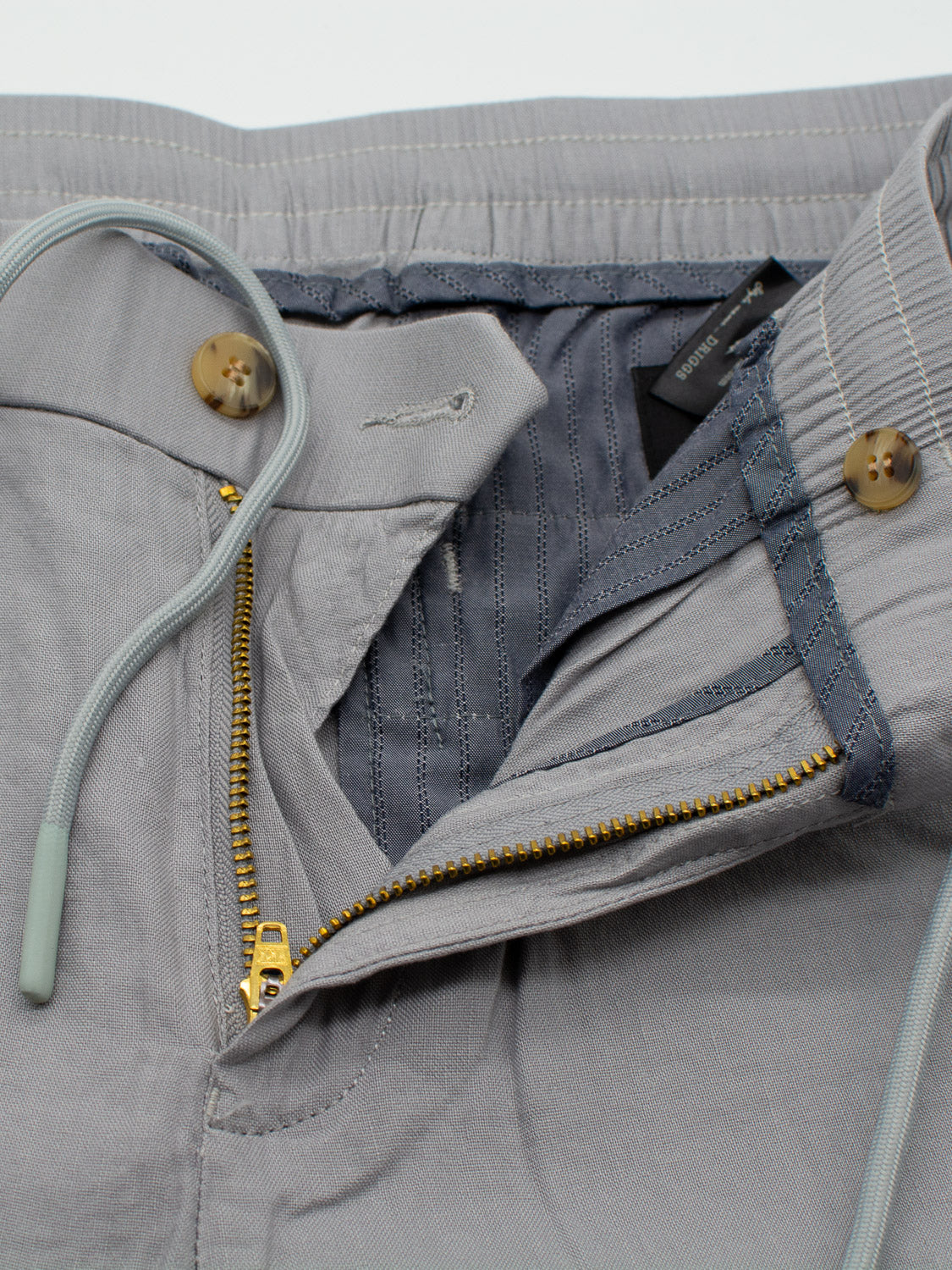 Close-up of Driggs Linen Blend Short by ID Menswear in gray, featuring a partially open zipper, drawstring waistband, button closure, and visible stitching. Crafted for comfort and ideal for warm weather casual wear.