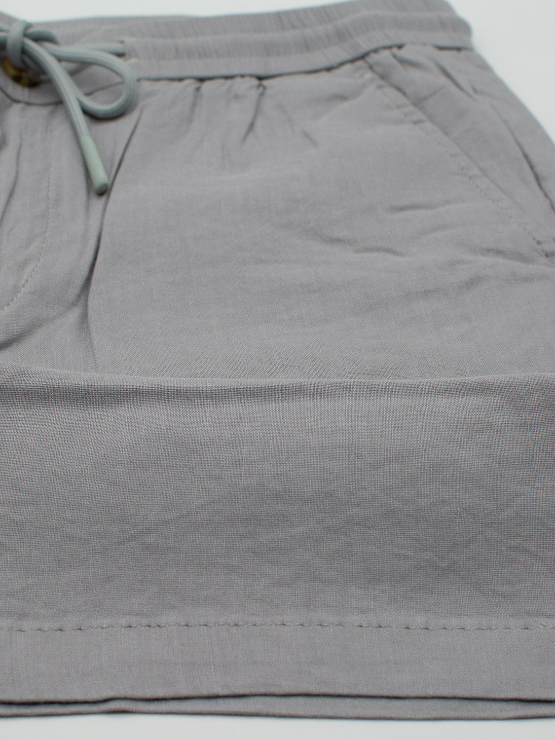 The Driggs Linen Blend Short from ID Menswear features a gray fabric with elastic waistband and drawstring, two side pockets, and a subtle texture. Lightweight and comfortable, theyre perfect for warm weather casual wear.