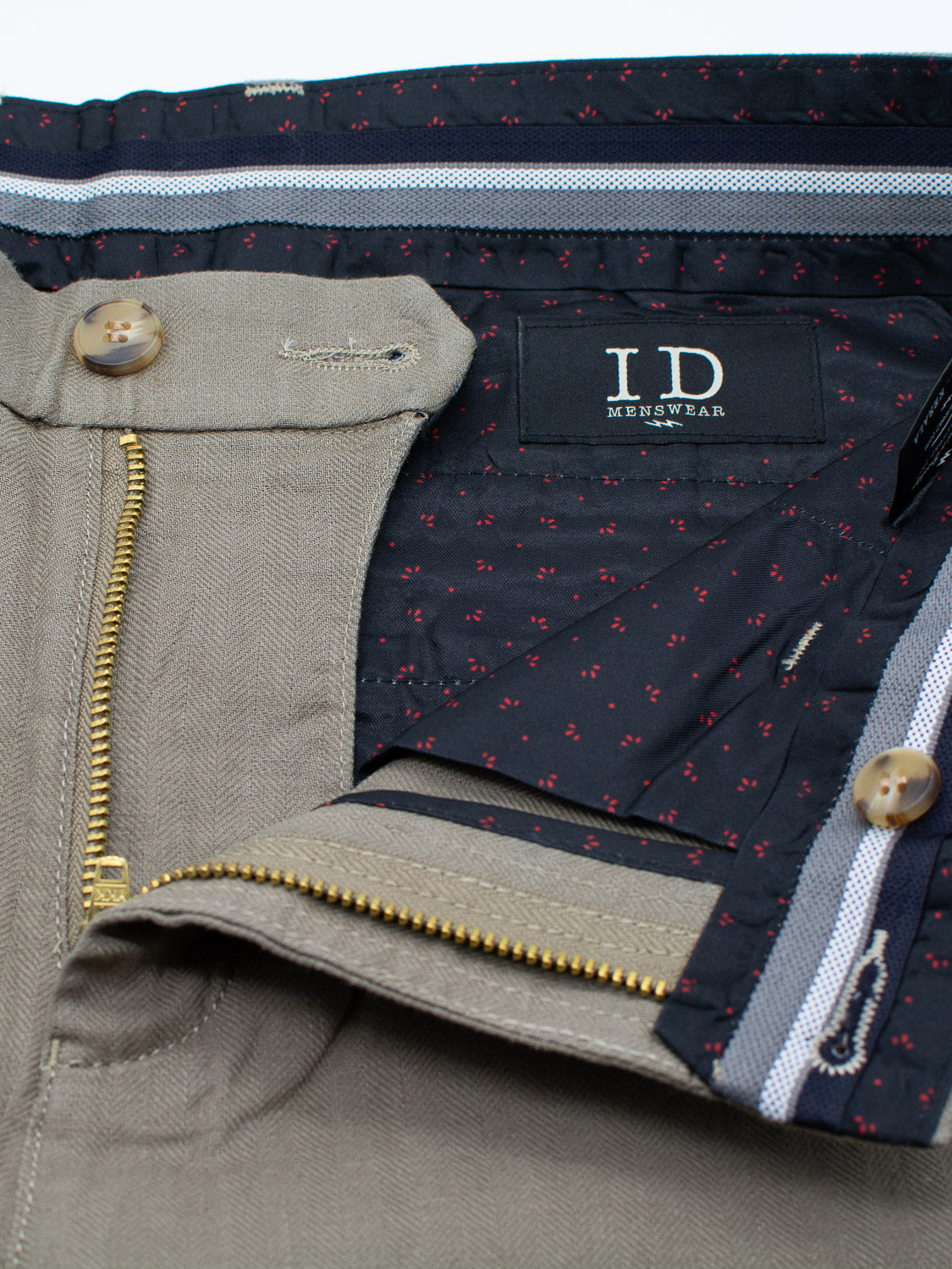 Close-up of Kerala Linen Blend Chino Short in khaki from ID Menswear, showing a relaxed fit with a partially unzipped gold zipper revealing a dark-patterned interior lining. The waistband has a button closure, showcasing the linen-cotton blend design.