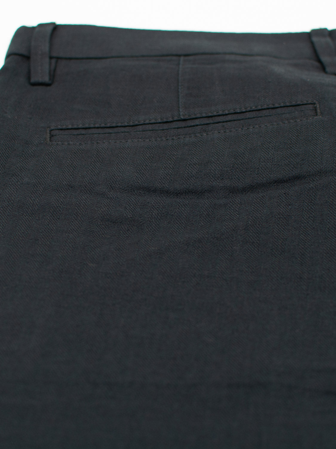Close-up of Kerala Linen Blend Chino Short by ID Menswear, showing a dark-colored, relaxed-fit design with a button-closure back pocket. The smooth linen-cotton blend fabric features visible stitching around the pocket.