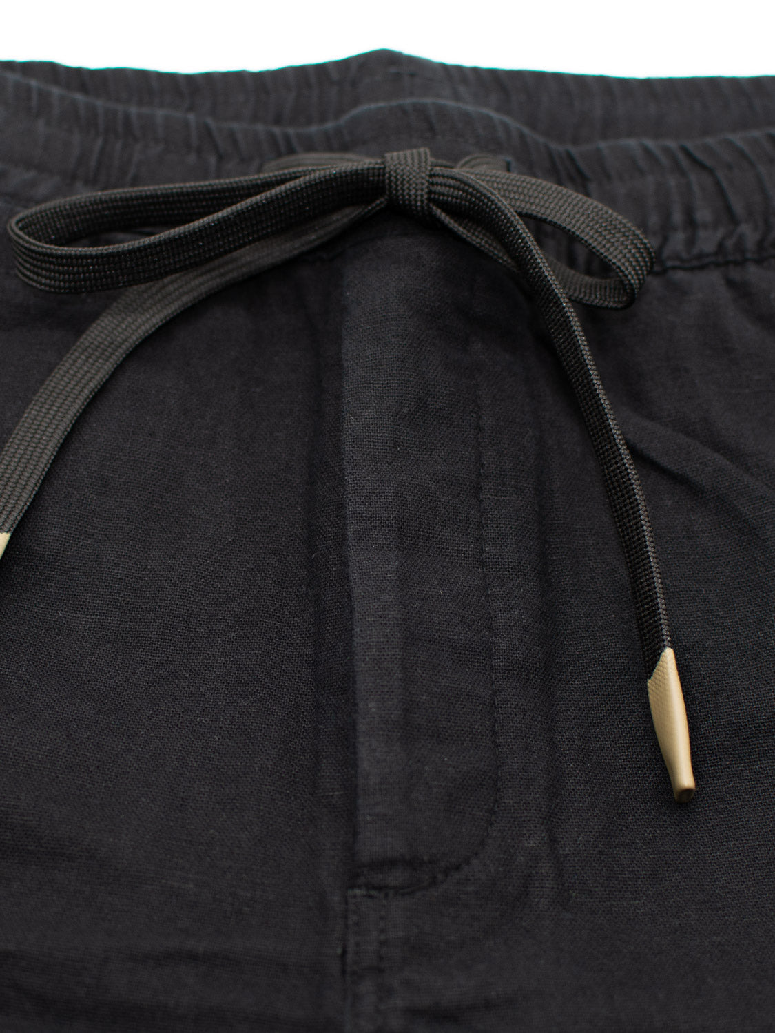 Close-up of the Kotao Linen Blend Drawstring Shorts by ID Menswear, showcasing a black design with an elastic waistband and a beige-tipped drawstring tied in a bow at the front, perfect for summer.