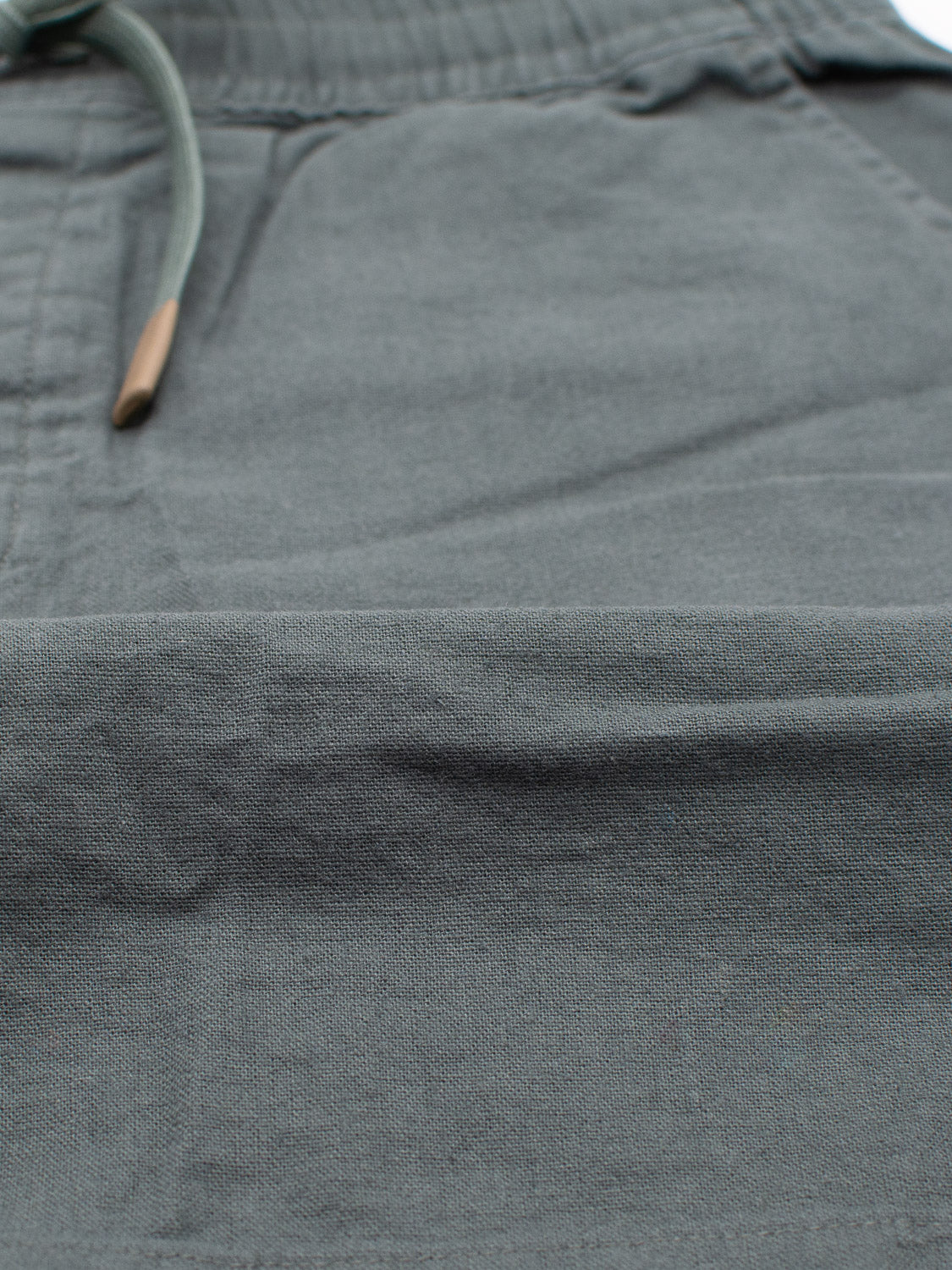 Close-up of Kotao Linen Blend Drawstring Short by ID Menswear, highlighting the gray fabric and drawstring waistband with metal tips. Perfect comfortable warm weather option for casual or lounge wear styles.