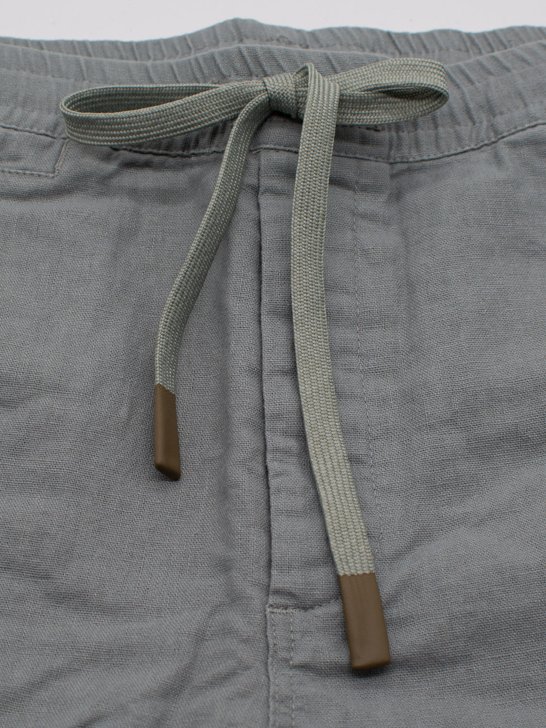 Close-up of Kotao Linen Blend Drawstring Short by ID Menswear in gray, featuring a visible waistband with light gray drawstrings and brown tips. The fabric appears soft and textured, making it perfect for summer.