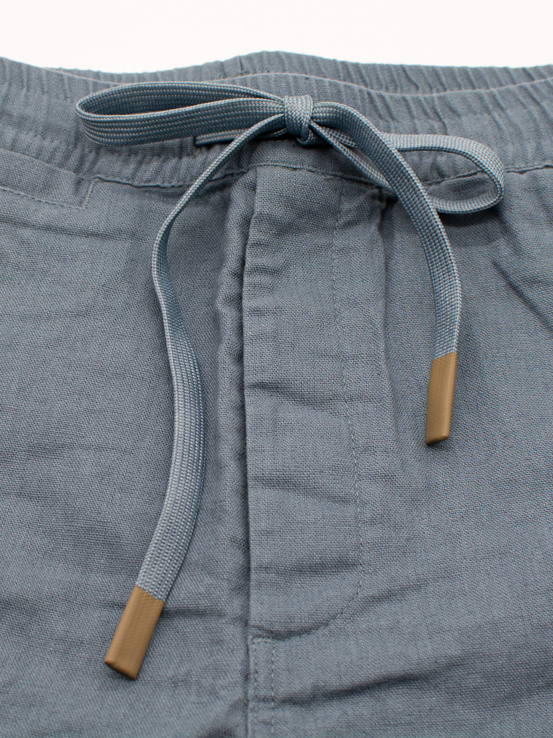Close-up of Kotao Linen Blend Drawstring Short by ID Menswear, featuring gray linen blend fabric with an elastic waistband and bow-tied string. The brown-tipped drawstring adds style, while the soft, slightly textured material is ideal for sunny summer days.