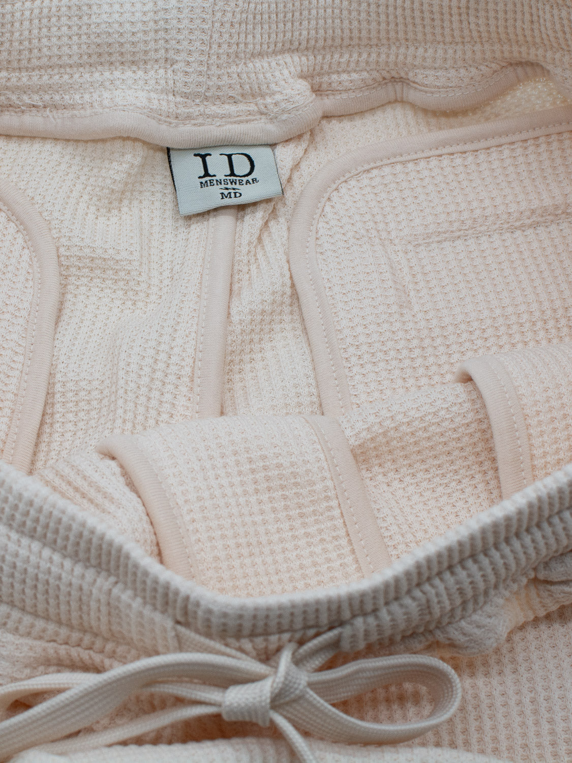 A textured beige bathrobe has a label saying ID Menswear and is reminiscent of the comfort found in the Walker Waffle Knit Short, featuring a drawstring tie at the bottom.