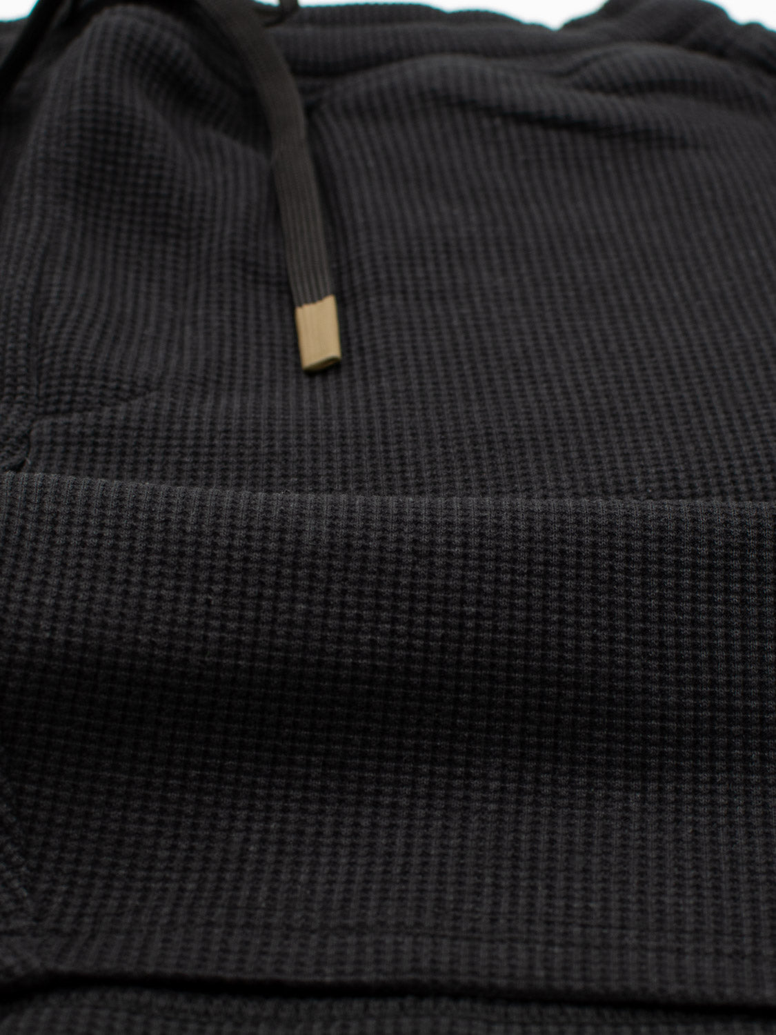 Close-up of ID Menswears Walker Waffle Knit Short in a dark textured fabric, featuring a subtle waffle pattern and a small black drawstring with gold-colored tips.
