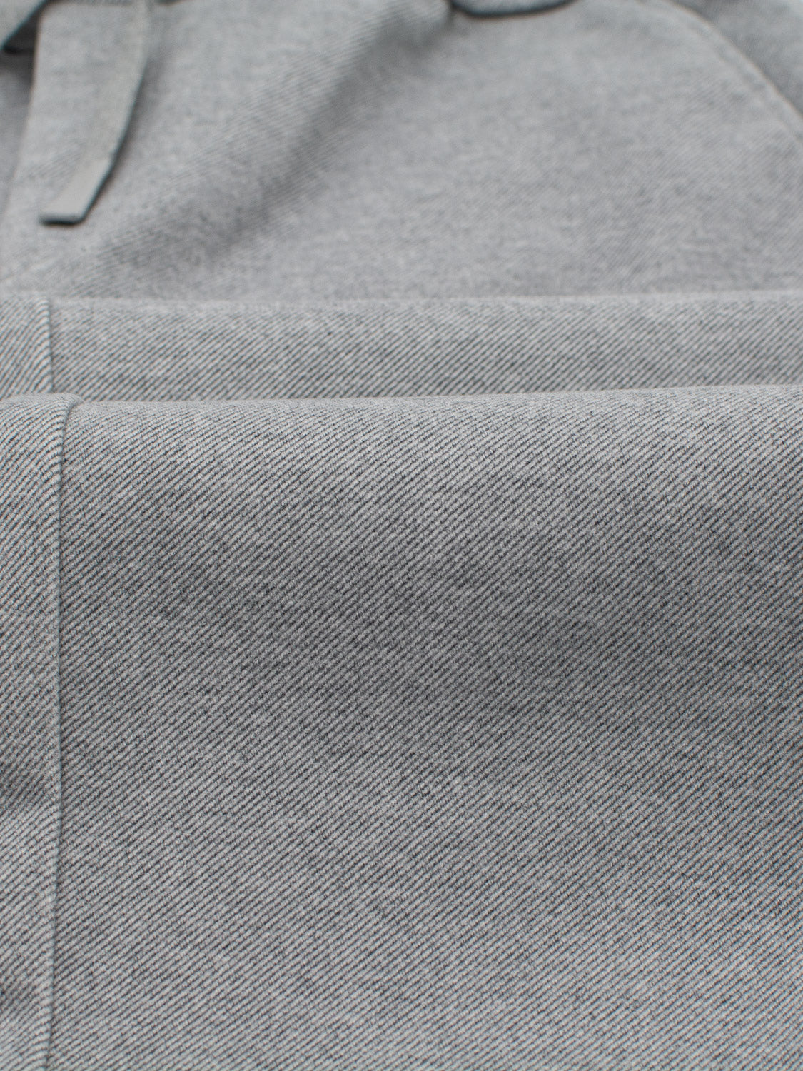 Close-up of gray brushed polyester fabric with a subtle textured pattern, showcasing seams and stitching. This material is from ID Menswears Brighton Brushed Polyester Rayon Pant.
