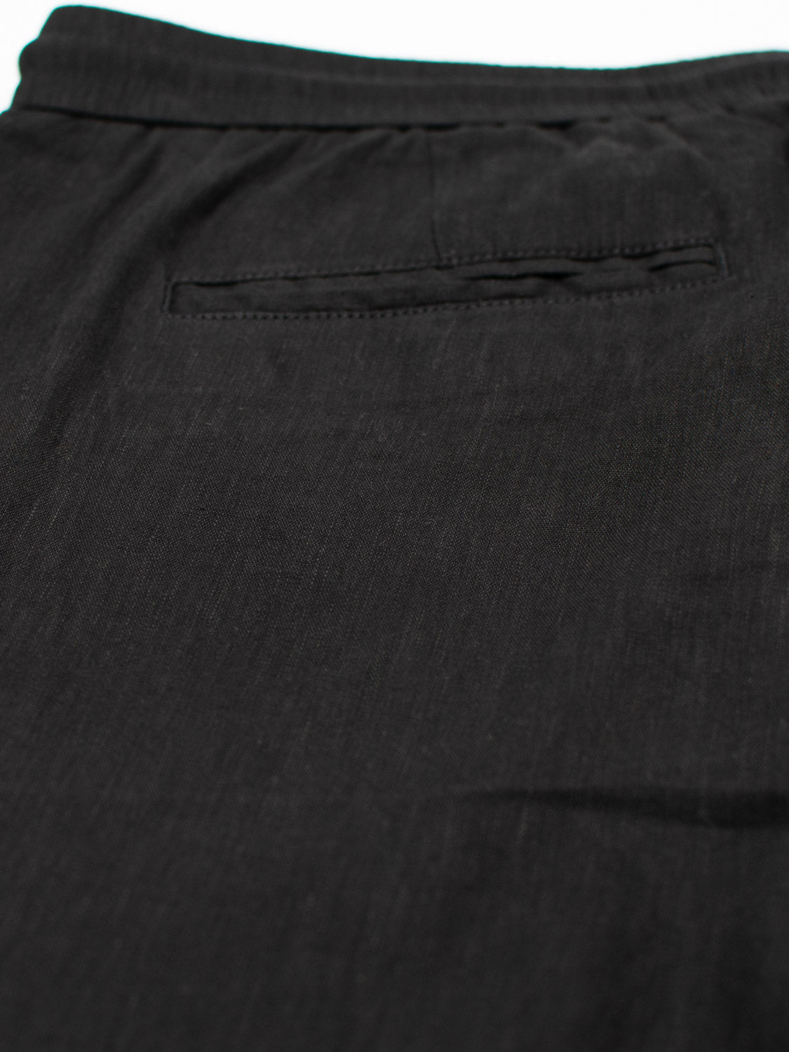 Close-up of a black ID Menswear Bedford23 Linen Blend Drawstring Pant with a horizontal slit back pocket. This lightweight, comfortable pant features slightly textured fabric with the pocket blending seamlessly into the material.